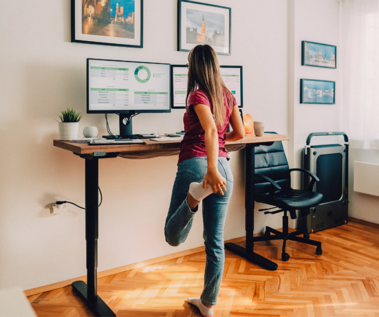 woman working at a standing desk stretching legs